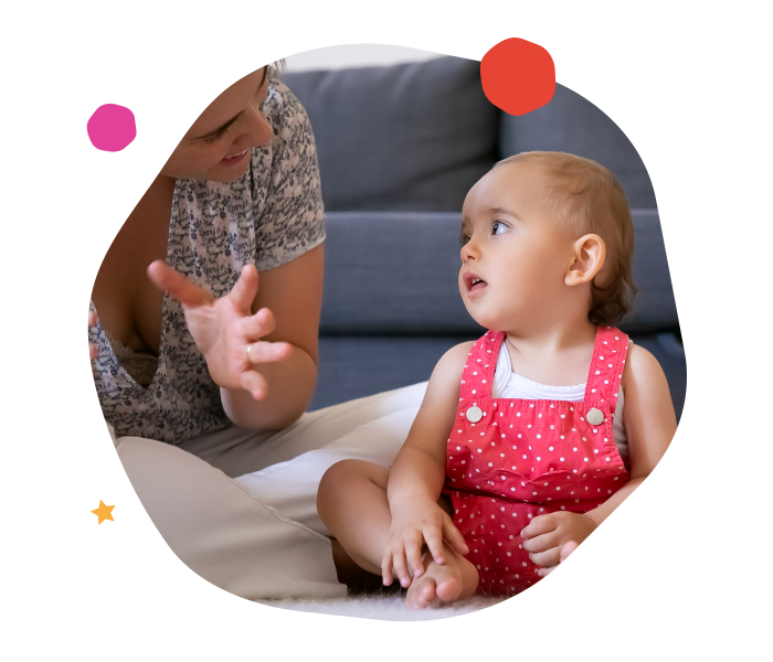 Parent faisant un signe de la main à un bébé assis qui le regarde attentivement